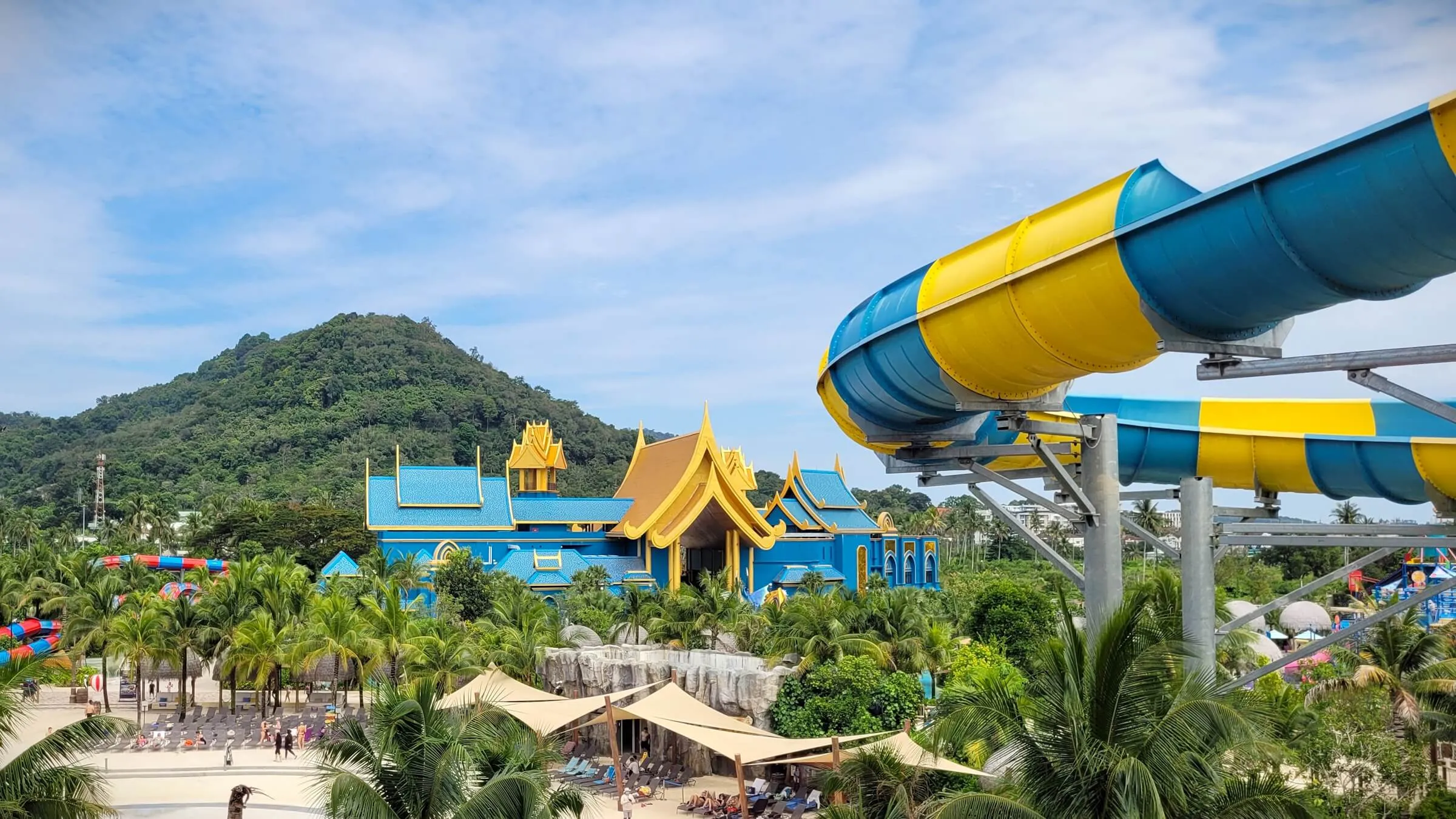 A blue-and-gold Thai-style palace among palms at Andamanda, with a yellow and blue slide tube in front